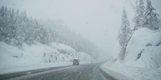 在高速公路上行驶的汽车挡风玻璃上飘落的雪