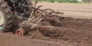 用拖拉机犁田，为种植农作物准备土壤。特写的运动拖拉机车轮和设备附加到它