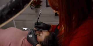 主美容师的手的侧面视图测量眉毛的比例，用特殊的工具涂上颜料。microblading的概念