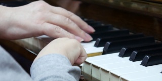 一个小孩和一个老太太在一起弹钢琴的手的特写