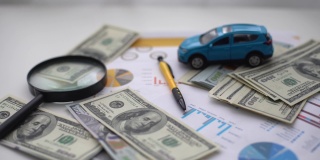 汽车保险的概念。汽车模型驾驶在金钱和保险文件的背景