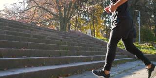 近距离的年轻亚洲男子运动员腿跑上楼梯训练激烈的有氧运动锻炼男性跑步者的脚在台阶上慢跑在城市背景