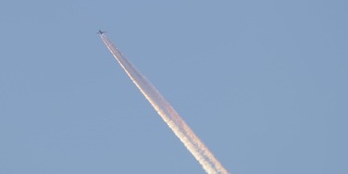 远处的喷气式客机在晴朗的蓝天上高空飞行，留下白色的烟迹。航空运输的概念