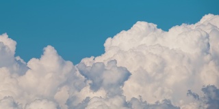 白色蓬松的积云在夏天的蓝天上逐渐形成。移动和变化的云景天气