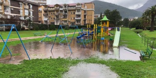 雨水滴落在孩子们的操场和大水坑上，在茂盛的草地上，住宅区靠近森林山