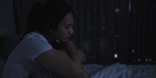亚洲妇女躺在白色的床上在卧室里看起来担心或思考一些关于她的生活或工作在半夜在家里。