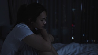 亚洲妇女躺在白色的床上在卧室里看起来担心或思考一些关于她的生活或工作在半夜在家里。视频素材模板下载