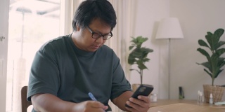 亚洲男子用手机做财务计算和记录