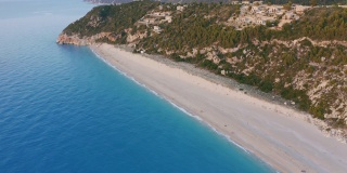 鸟瞰希腊爱奥尼亚岛莱夫卡达美丽的米洛斯海滩。日落金色的阳光和蓝绿色大海中质朴平静的波浪