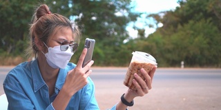 一名亚洲妇女在路边的咖啡馆里，以汽车行驶为背景，拍摄一杯冰咖啡。