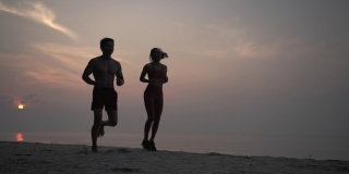 一对亚洲情侣在沙滩上慢跑。