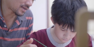 亚洲男孩和父亲在家里画水彩画