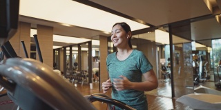 亚洲妇女在健身房的跑步机上跑步