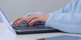 女商人在办公室用笔记本电脑工作。在笔记本电脑键盘上打字的自由作家的手。女性在封锁期间在线远程工作，4k库存视频
