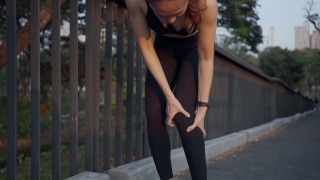 运动妇女在公园户外慢跑运动时膝盖疼痛，身体状况疼痛关节韧带问题。视频素材模板下载