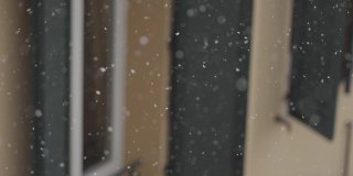 雪花在风雪中飘落在院子里，拉近了窗户的细节。缓慢的运动。