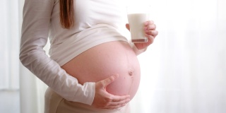 快乐的孕妇喝一杯新鲜的牛奶。健康的钙，茶点