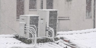 屋顶上有空调，暴风雪时雪花落在屋顶上，屋后有树。缓慢的运动。