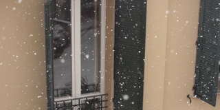 雪花在风雪中飘落在院子里，拉近了窗户的细节。缓慢的运动。
