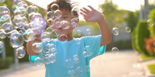 亚洲小孩在公园玩泡泡。幸福和夏日的概念