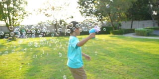 亚洲小孩在公园玩泡泡。幸福和夏日的概念