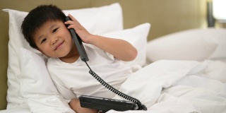 亚洲男孩打电话到酒店的接待处。接待和客户服务的理念