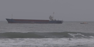 在暴风雨天气下，一艘油轮沿着一艘引航船在波涛汹涌的海面上行驶的特写镜头