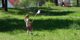 在阳光明媚的夏日里，可爱的小女孩一边走一边用勺子网捉蝴蝶
