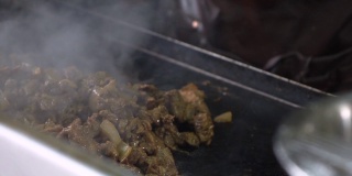 成堆的肉陈列在墨西哥街头小贩的烧烤架上，taquero sautéing慢镜头中的肉。