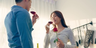 亚洲年轻情侣在情人节举杯畅饮。可爱浪漫的新婚男女在家里厨房共进晚餐庆祝结婚纪念日