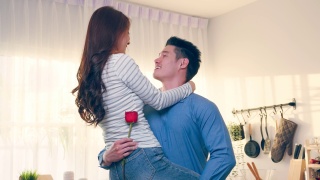 亚洲青年惊喜送玫瑰给美丽的女友。迷人浪漫的新婚男女花时间在房子里一起庆祝周年纪念日和情人节。视频素材模板下载