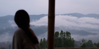 模糊的一个女人坐在看美丽的山景在雾天