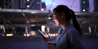 女商人在晚上走路时使用智能手机