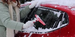 年轻女子正在清理车上的雪