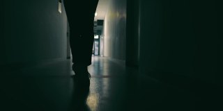 黑暗的走廊上女性腿的剪影。一个女人在走廊尽头参加一个灯光会议