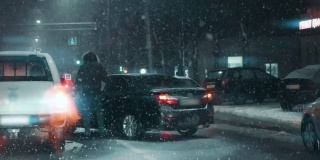 在傍晚雪天的交通高峰期，发生车祸或交通事故。两辆损坏的汽车在暴风雪中闪烁着车灯。慢动作