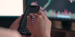 手指在智能手机上处理数据，显示器上显示加密货币图表