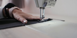 特写镜头:在服装厂，女工用缝纫机缝制织物