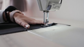 特写镜头:在服装厂，女工用缝纫机缝制织物视频素材模板下载
