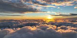 史诗般的无人机在日出时飞越云层。白色蓬松的云被早晨的太阳和橙色的黎明天空照亮。航拍，延时拍摄