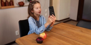 快乐微笑的小女孩拿着智能手机和远方的朋友视频通话
