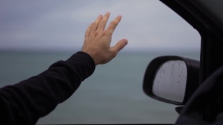 一个男人在雨天开车时，手正在接雨视频素材模板下载