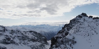 在法国的库尔舍维尔，雪山映衬着多云的天空，无人驾驶飞机在多云的日子里拍摄到令人惊叹的阿尔卑斯山脉被雪覆盖的山脊
