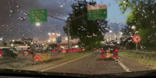 汽车内饰，汽车在雨溅的挡风玻璃上行驶。4K分辨率。