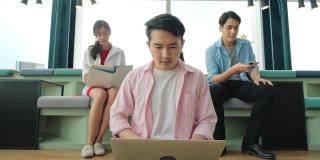 一群亚洲高中生在办公室会议室里开会，用笔记本电脑分析统计数据、分析市场，并考虑营销活动。
