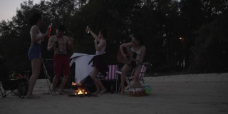 一群亚洲朋友在海滩上野营度假。