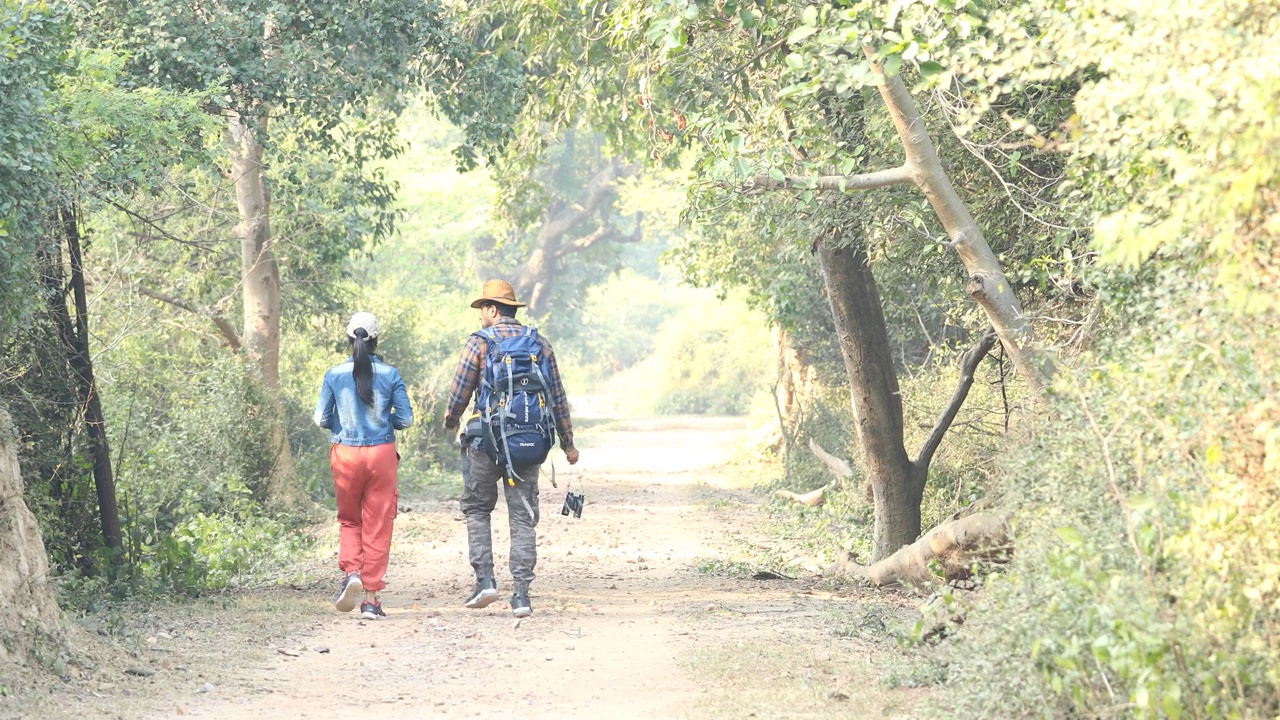 一对年轻夫妇在森林徒步旅行时用相机拍照