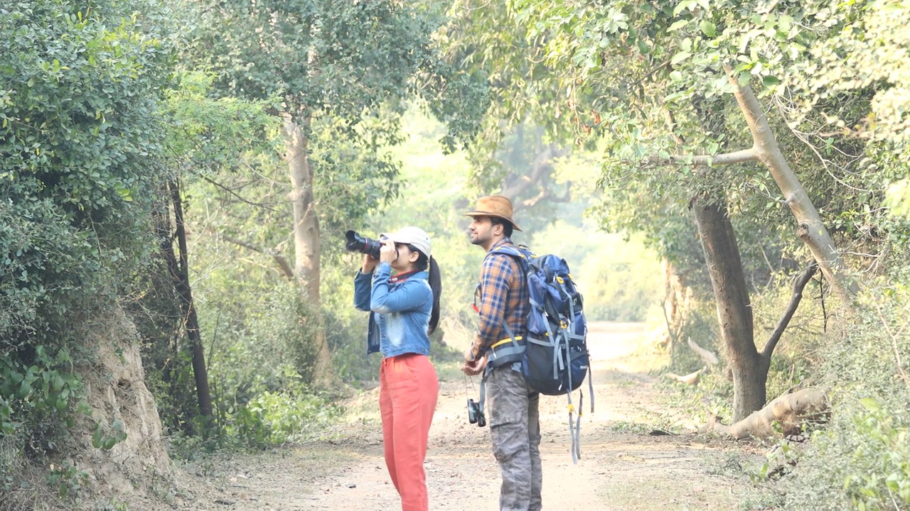 一对年轻夫妇在森林徒步旅行时用相机拍照