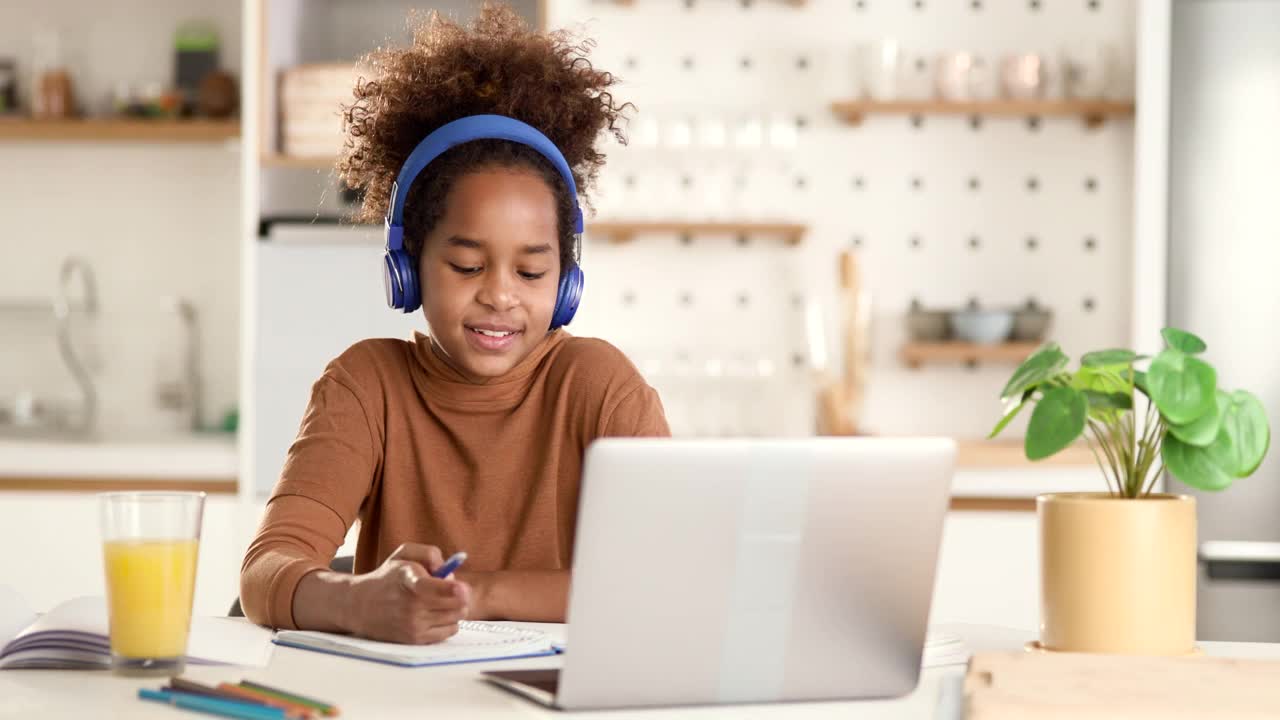 快乐的黑人女孩在家里的在线课堂上挥手。