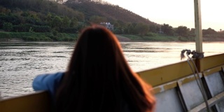 一名女性游客坐在湄公河上的一艘长尾船上的慢镜头后视镜
